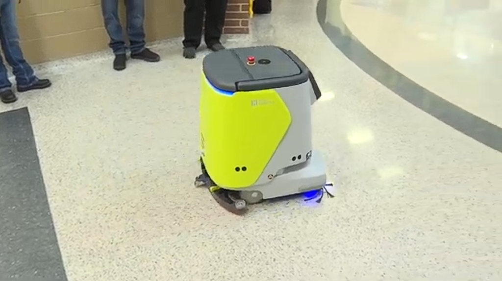 kids watching a robot clean school hallway